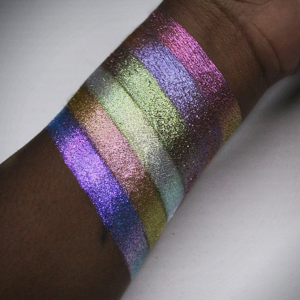 Arm swatches of all six Galápagos Palette shadows on deep skin tone on a beige background.