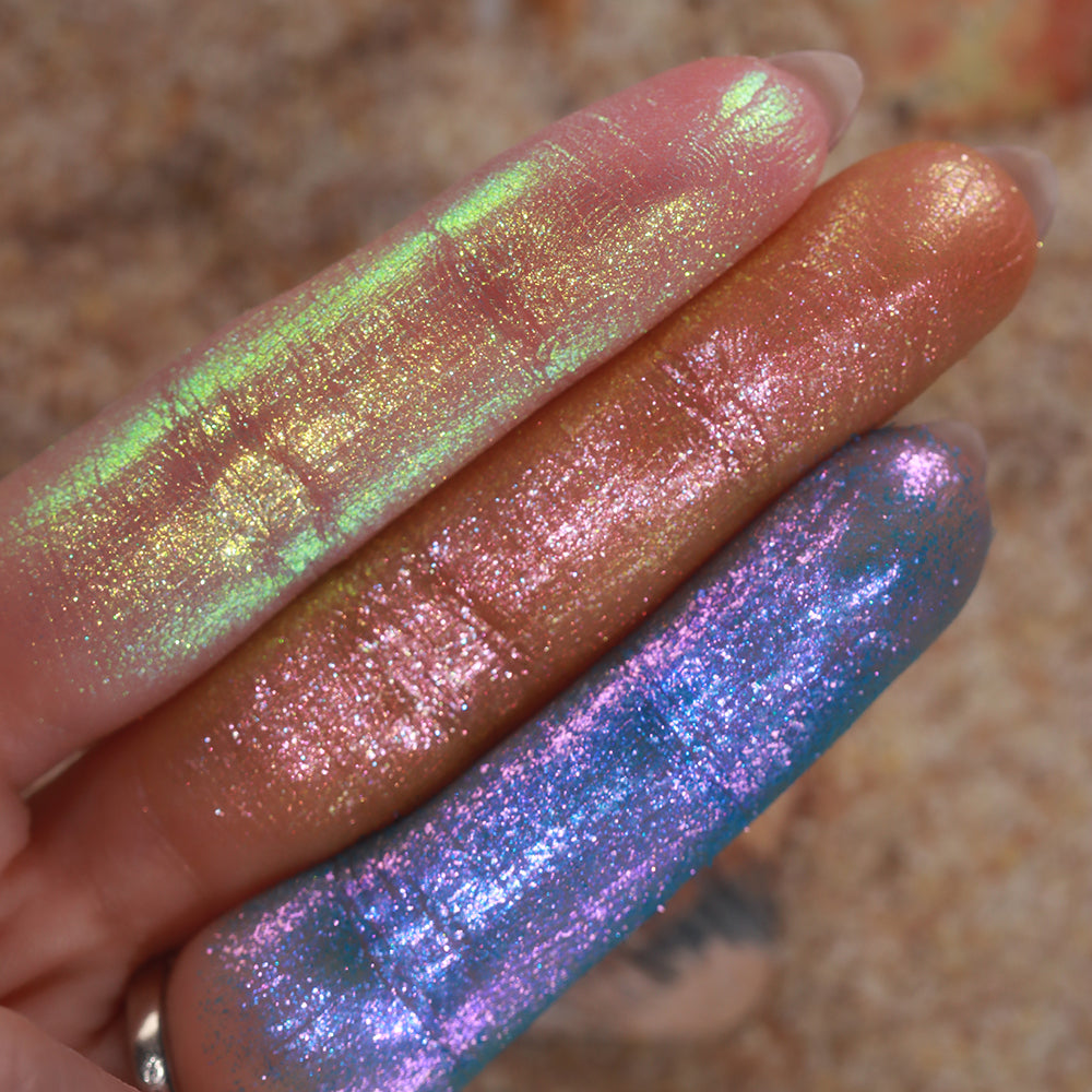 Three finger swatches of shadows from the Galápagos Palette, with sand in the background.